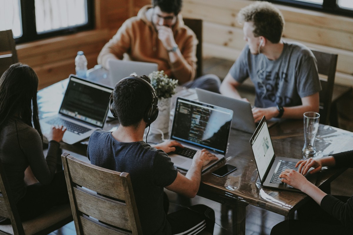 Equipo colaborando alrededor de una mesa con computadoras portátiles